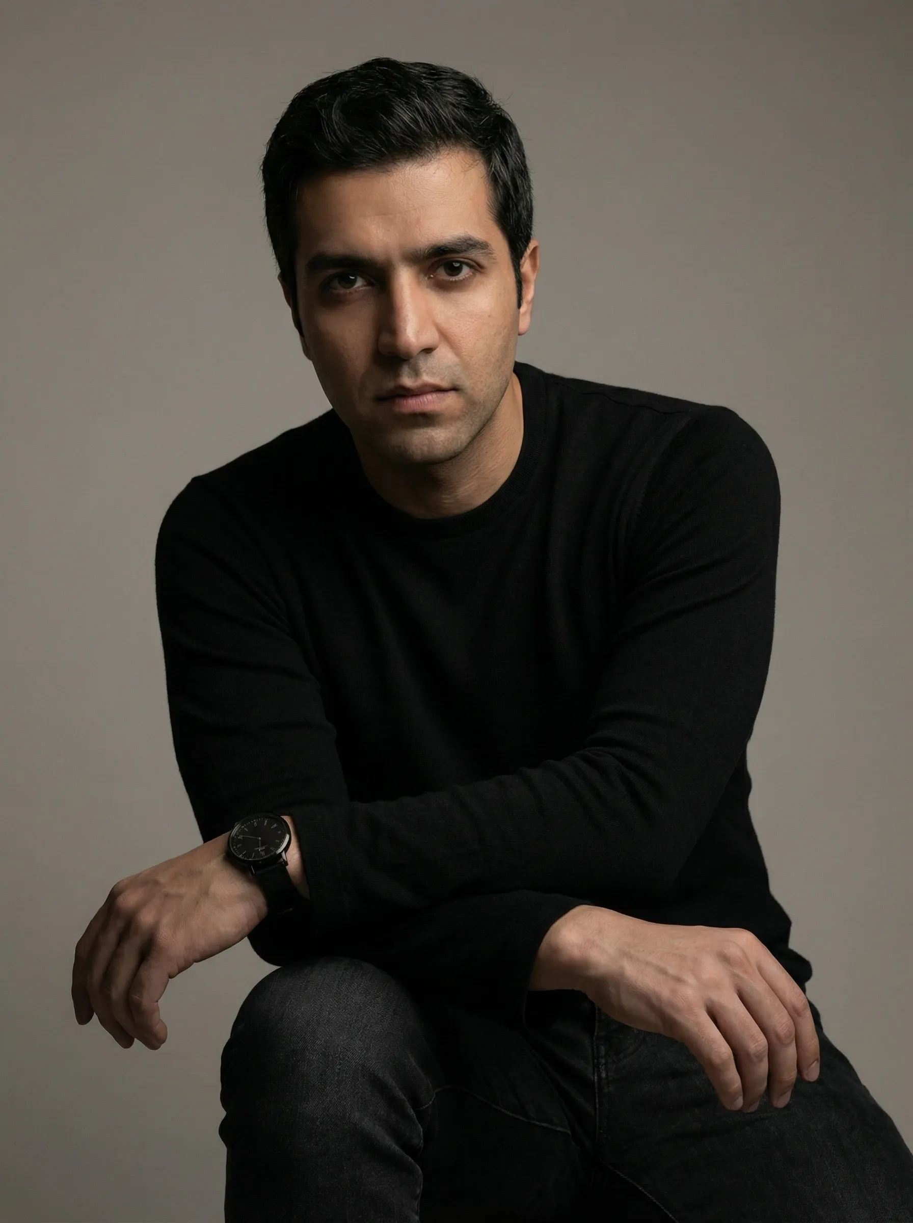 AI actor headshot — man in a black crew neck sweater seated against a soft gray background